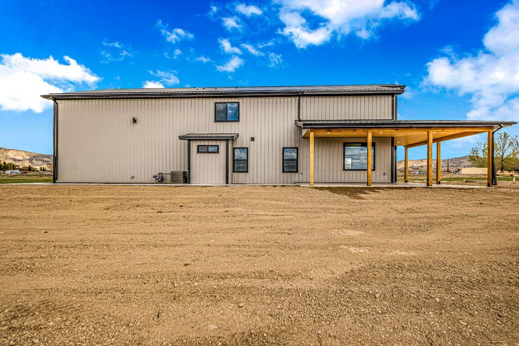 A large house is sitting in the middle of a dirt field.