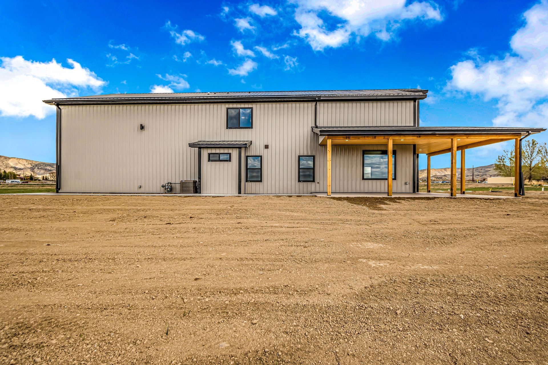 A large house is sitting in the middle of a dirt field.