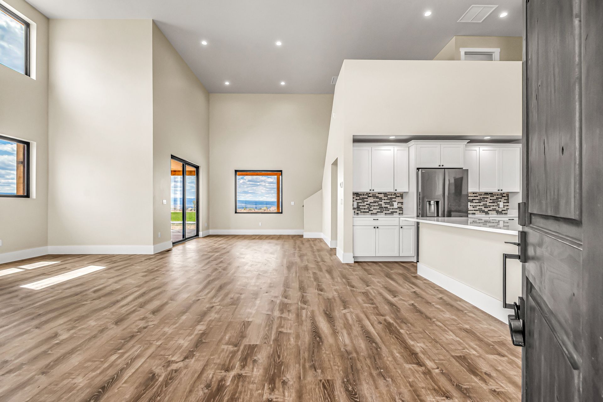A large empty room with hardwood floors and a kitchen.