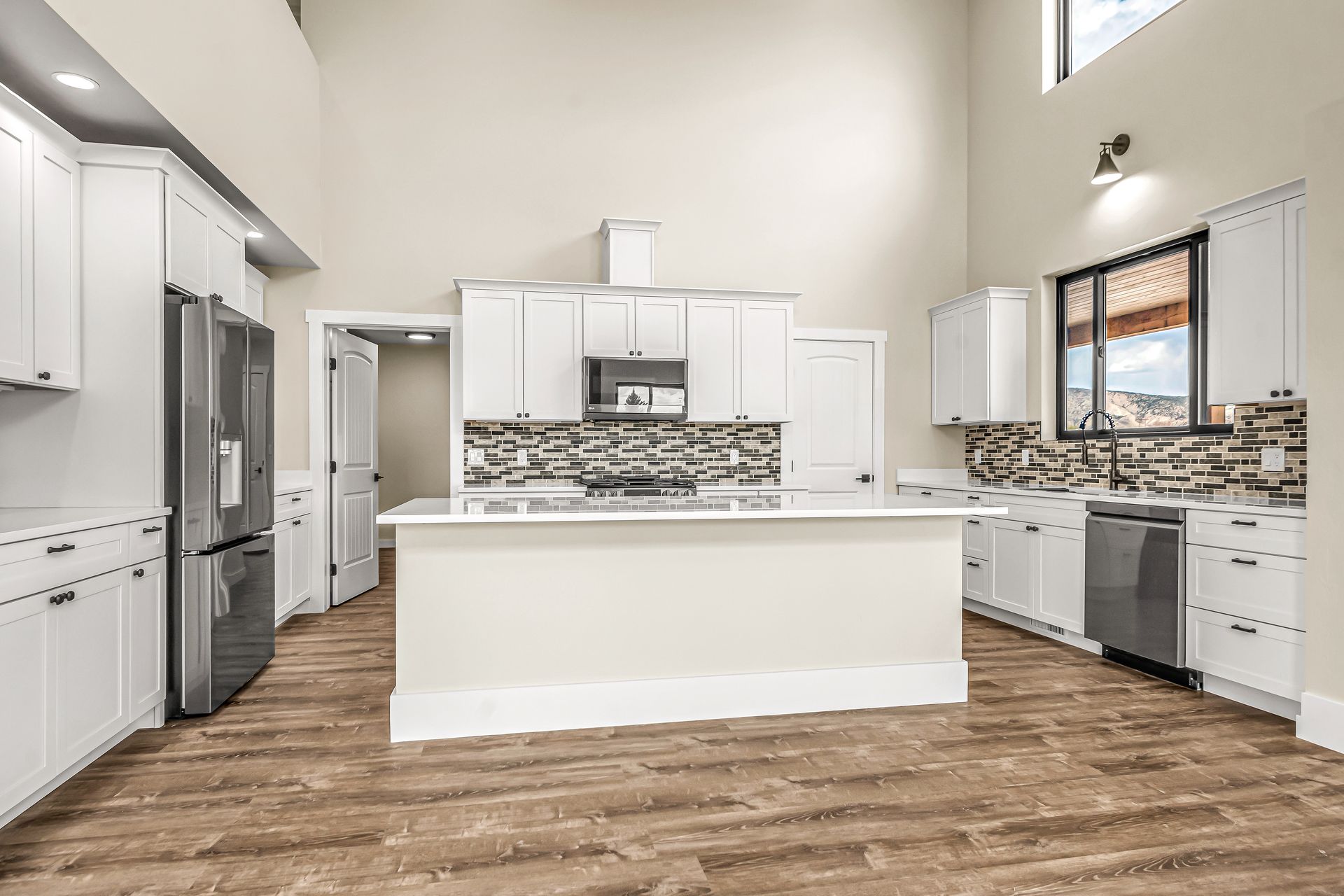 A kitchen with white cabinets , stainless steel appliances , and a large island.