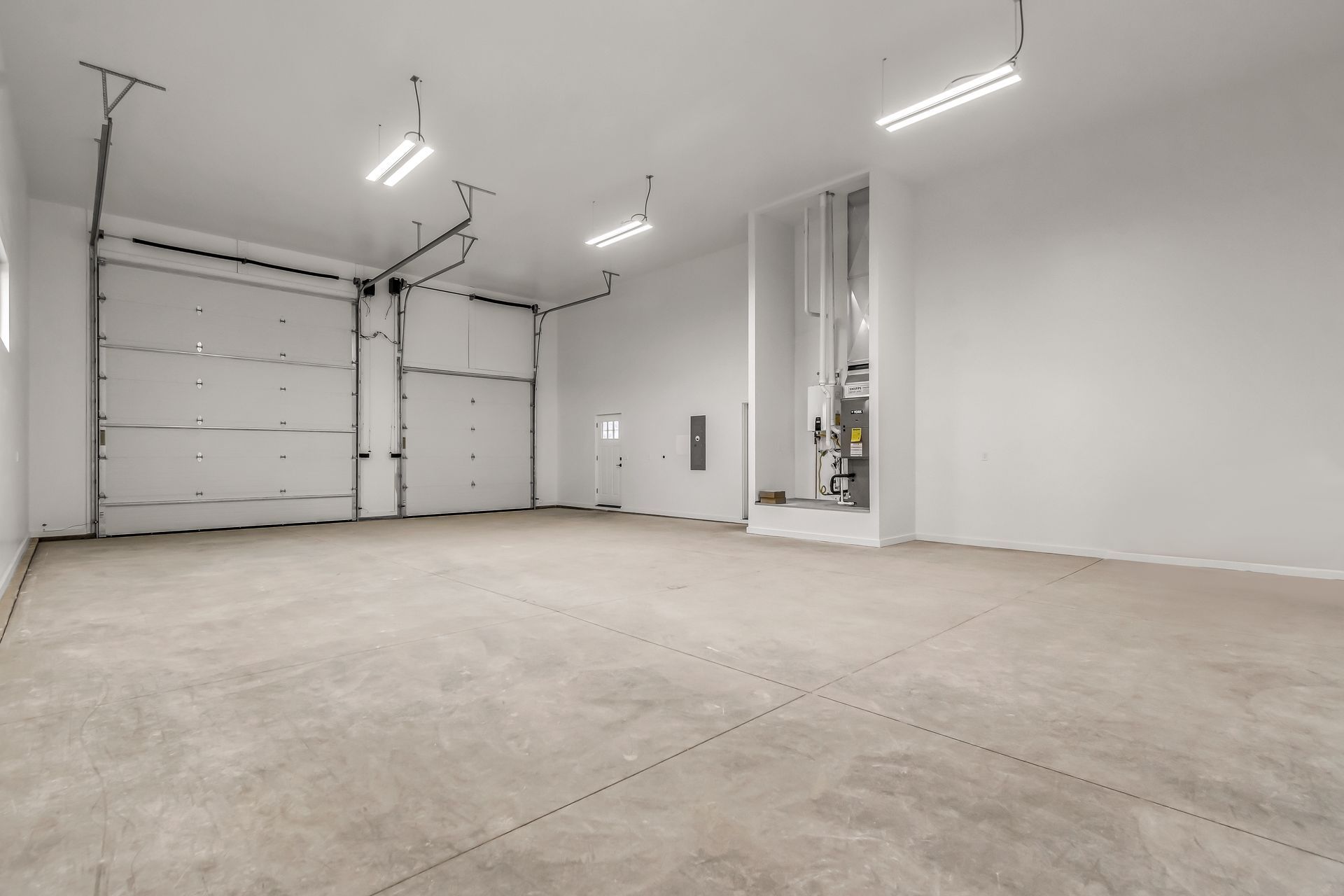 A large empty garage with a concrete floor and a garage door.