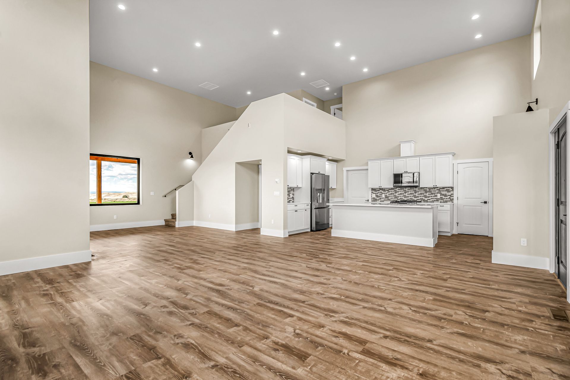 A large empty room with hardwood floors and a kitchen.