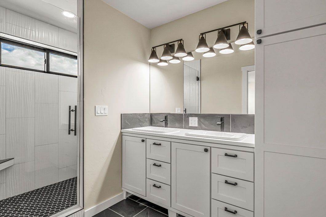 A bathroom with two sinks and a walk in shower.
