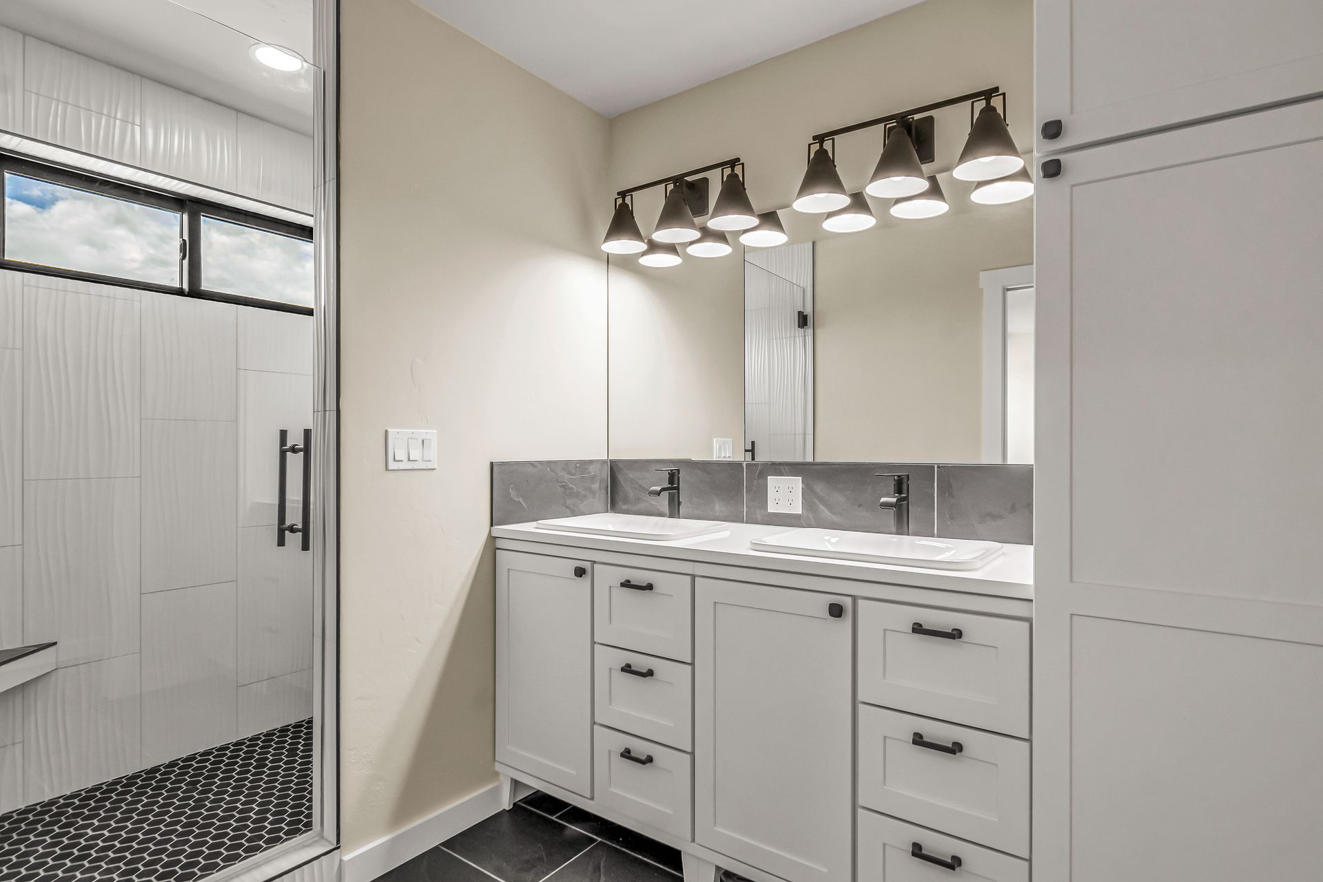 A bathroom with two sinks and a walk in shower.