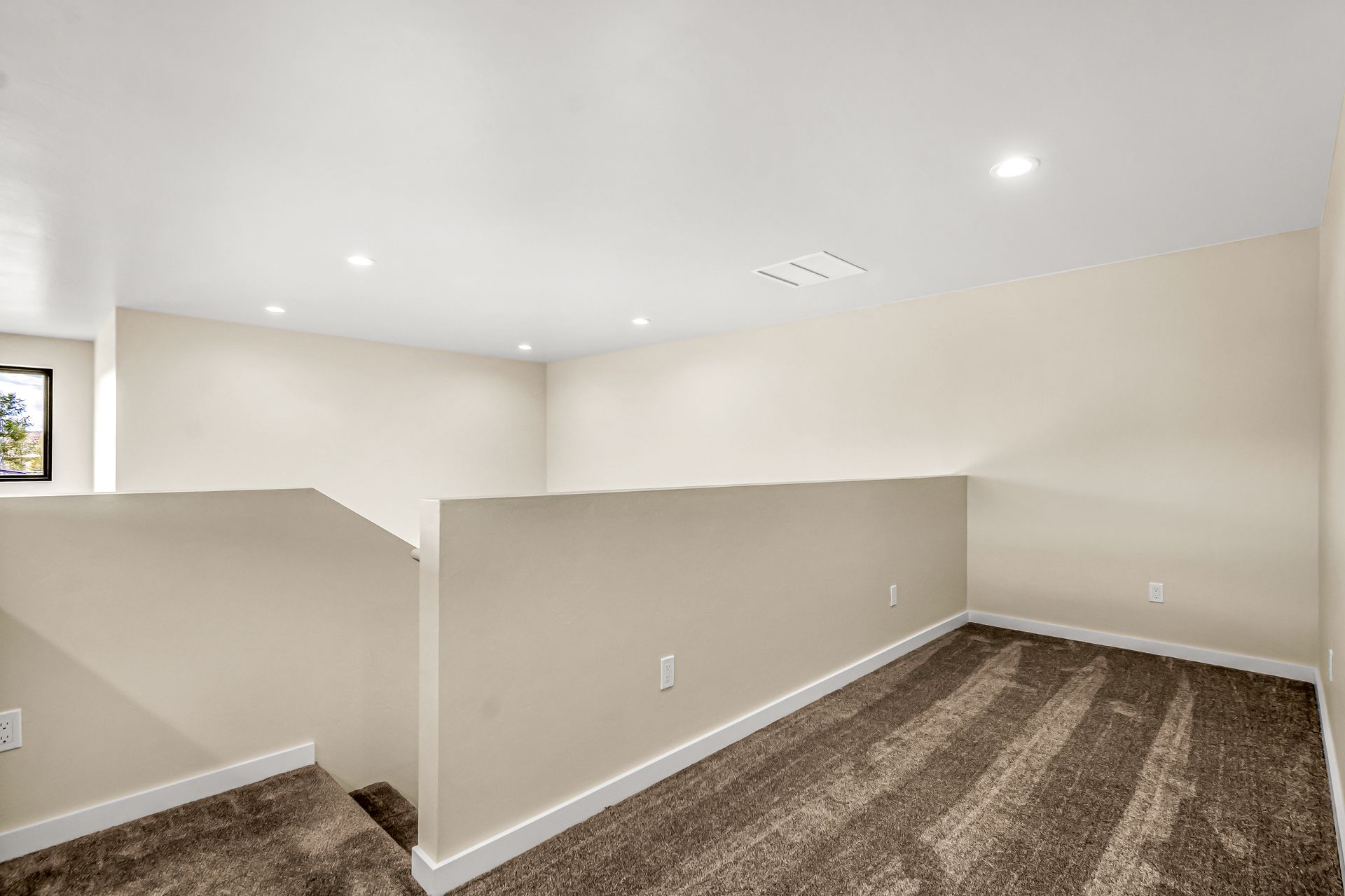 A room with a staircase and a carpeted floor in a house.