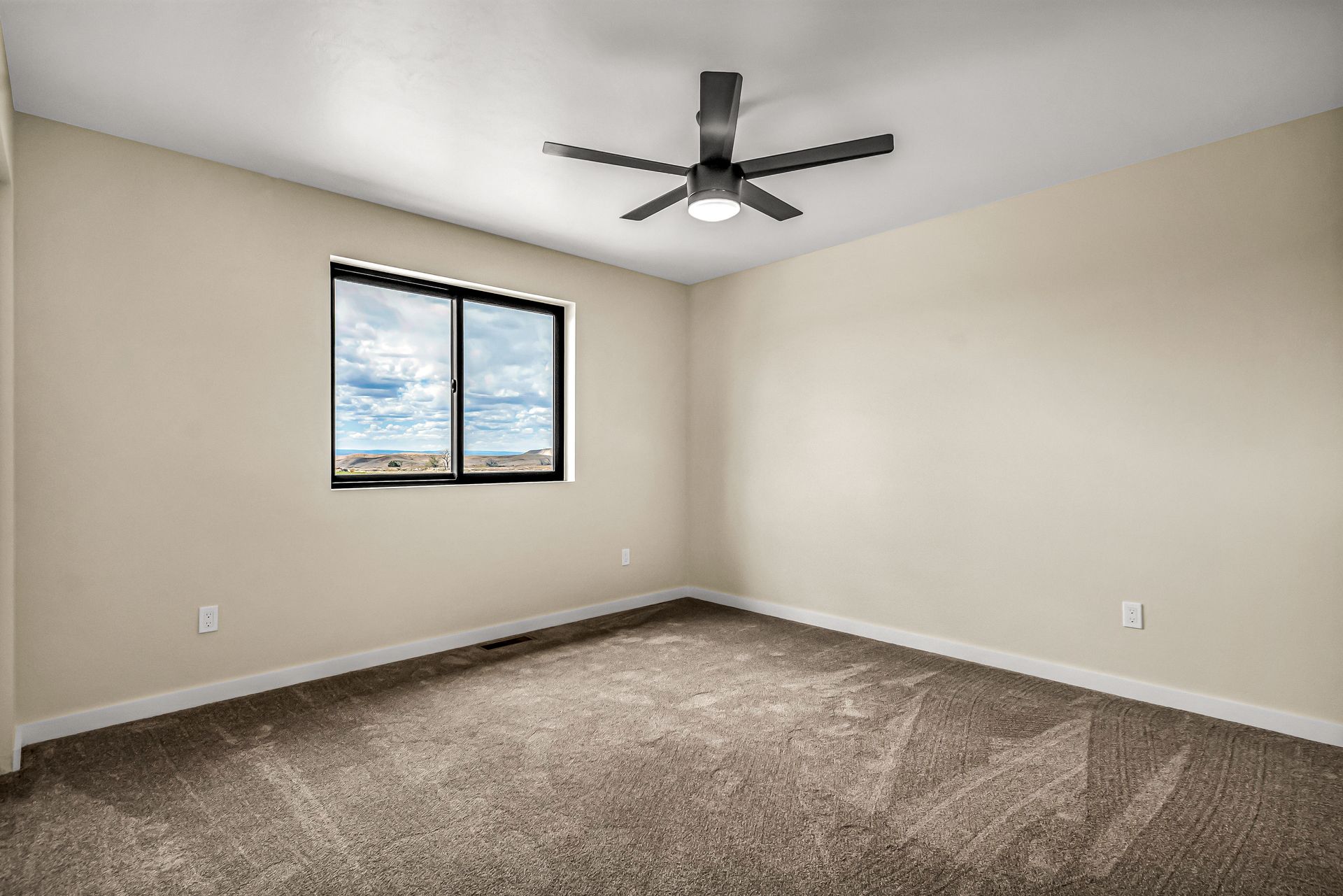 An empty bedroom with a ceiling fan and a window.