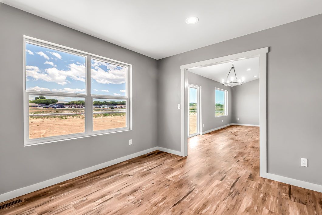 An empty room with hardwood floors and two windows.