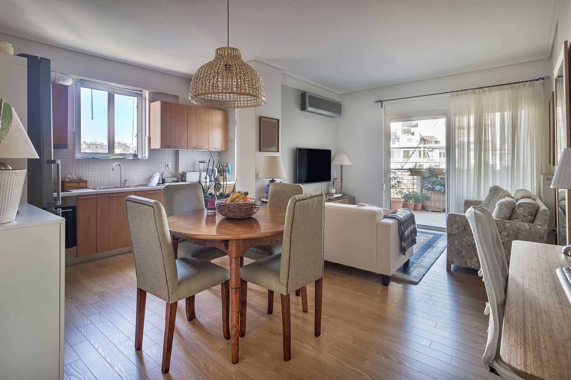 Open-plan living space with kitchen, dining table, and seating area leading to a balcony.