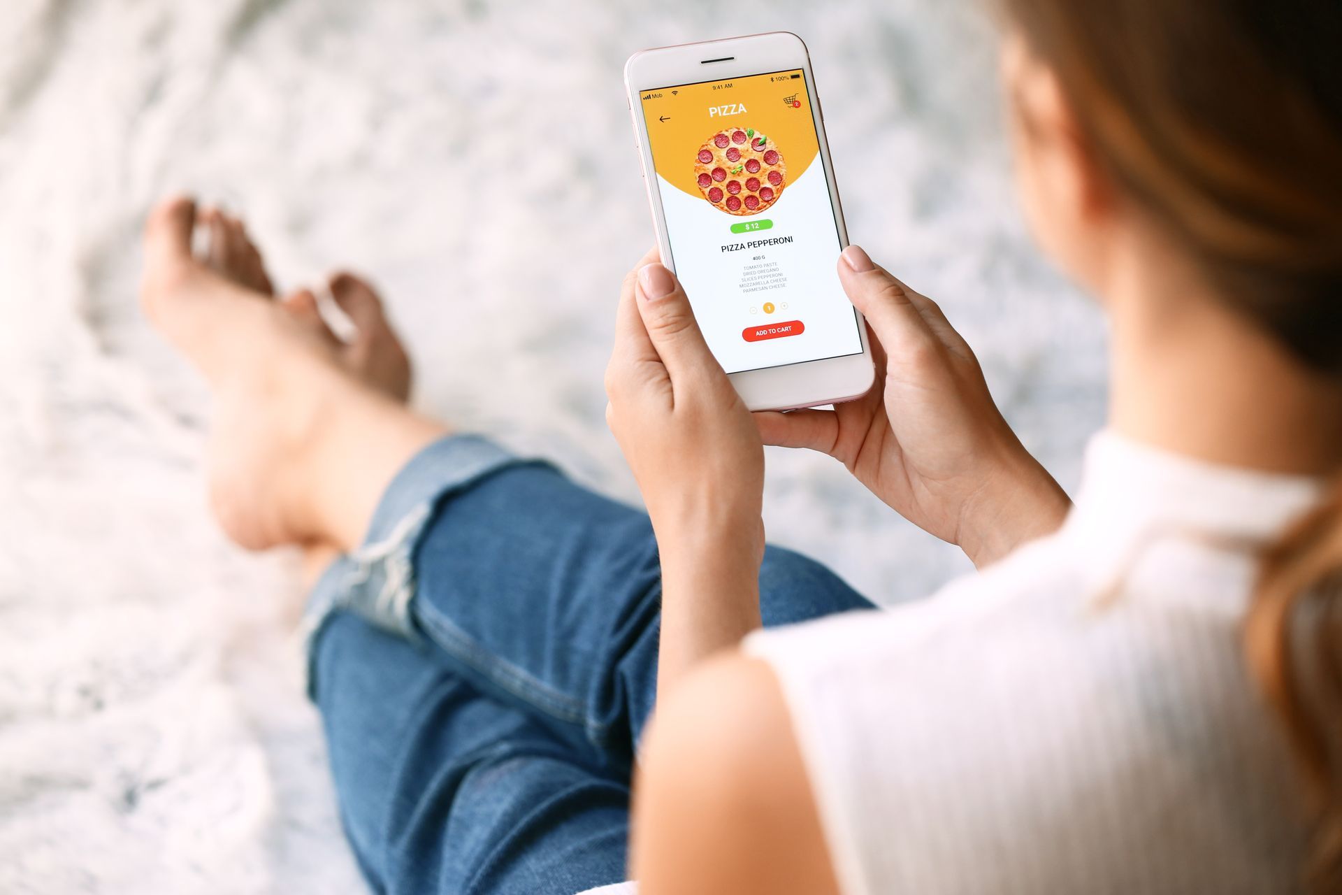 Person holding a phone, ordering pizza from an app.