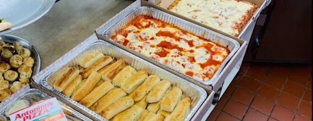 Trays of catered food: breadsticks, lasagna with melted cheese, and a casserole.