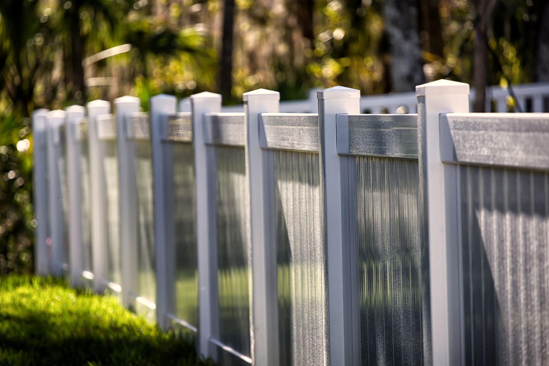 A close up of a white fence with trees in the background.