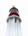 White lighthouse with a red lantern room against a bright sky