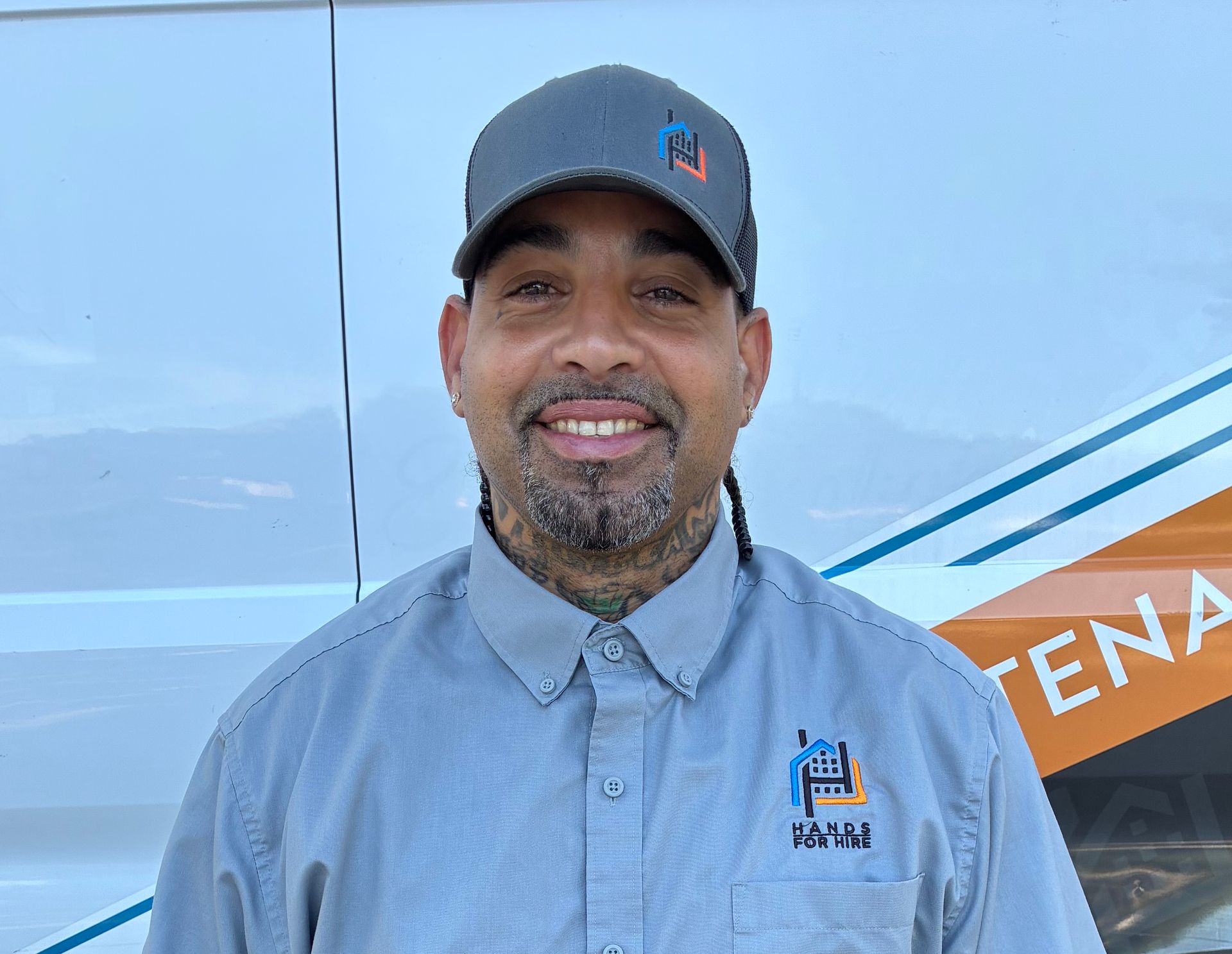 Man with beard wearing a black t-shirt with a logo, smiling.