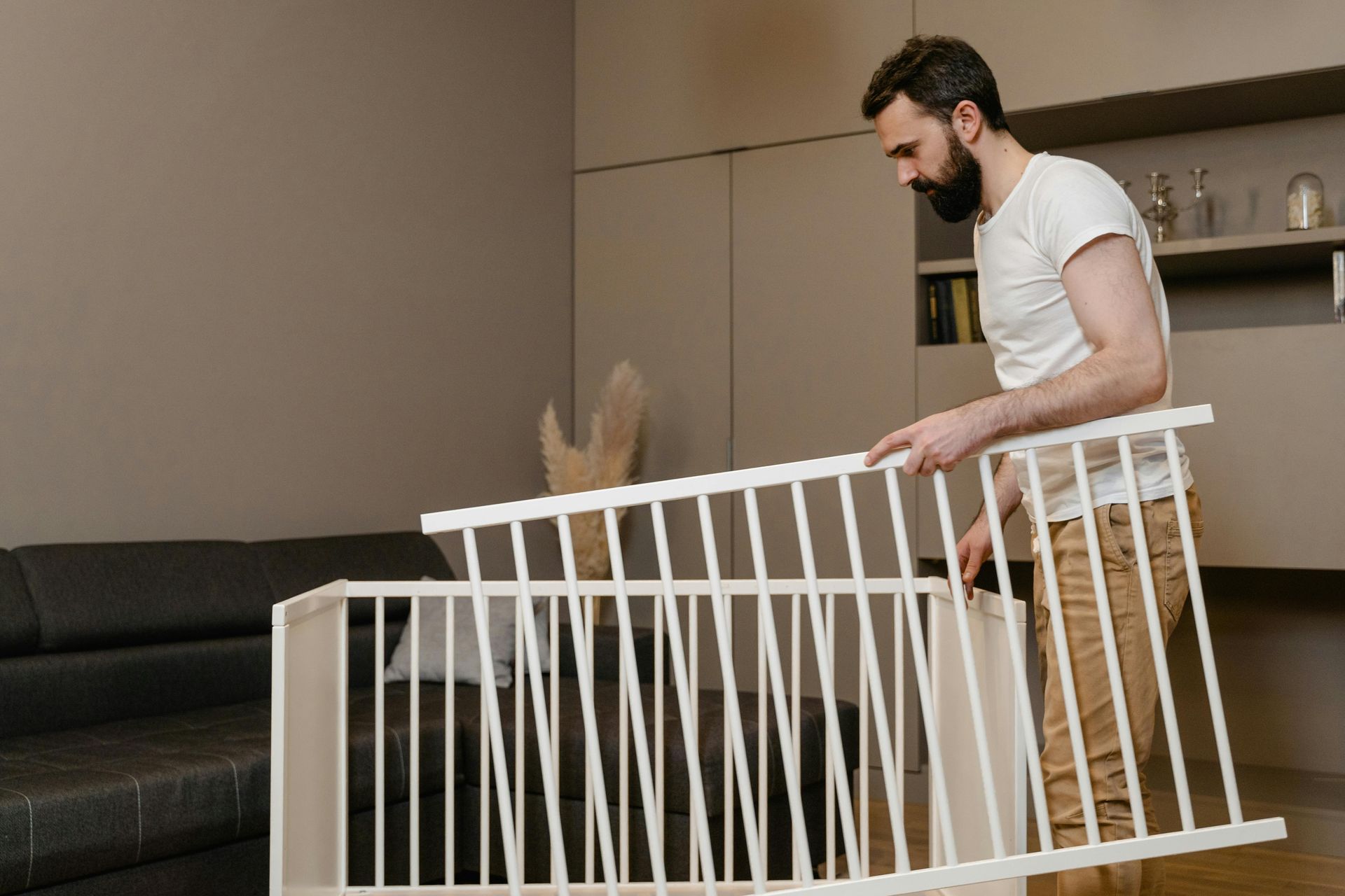 Man assembling white crib in living room.