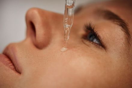 Close-up of a person’s face with eye drops being applied to one eye