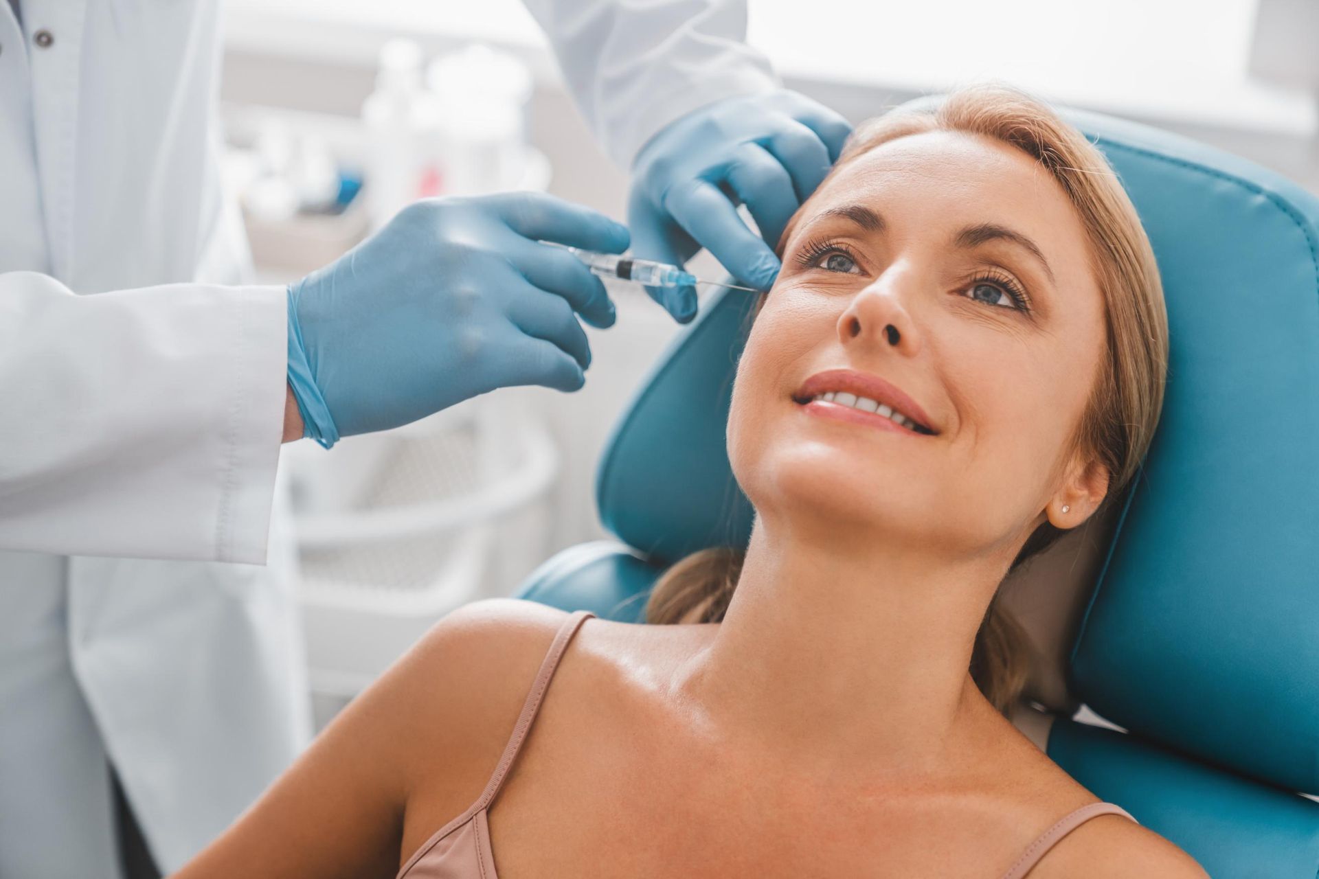 Dentist examining a smiling patient in a clinic with blue gloves and chair