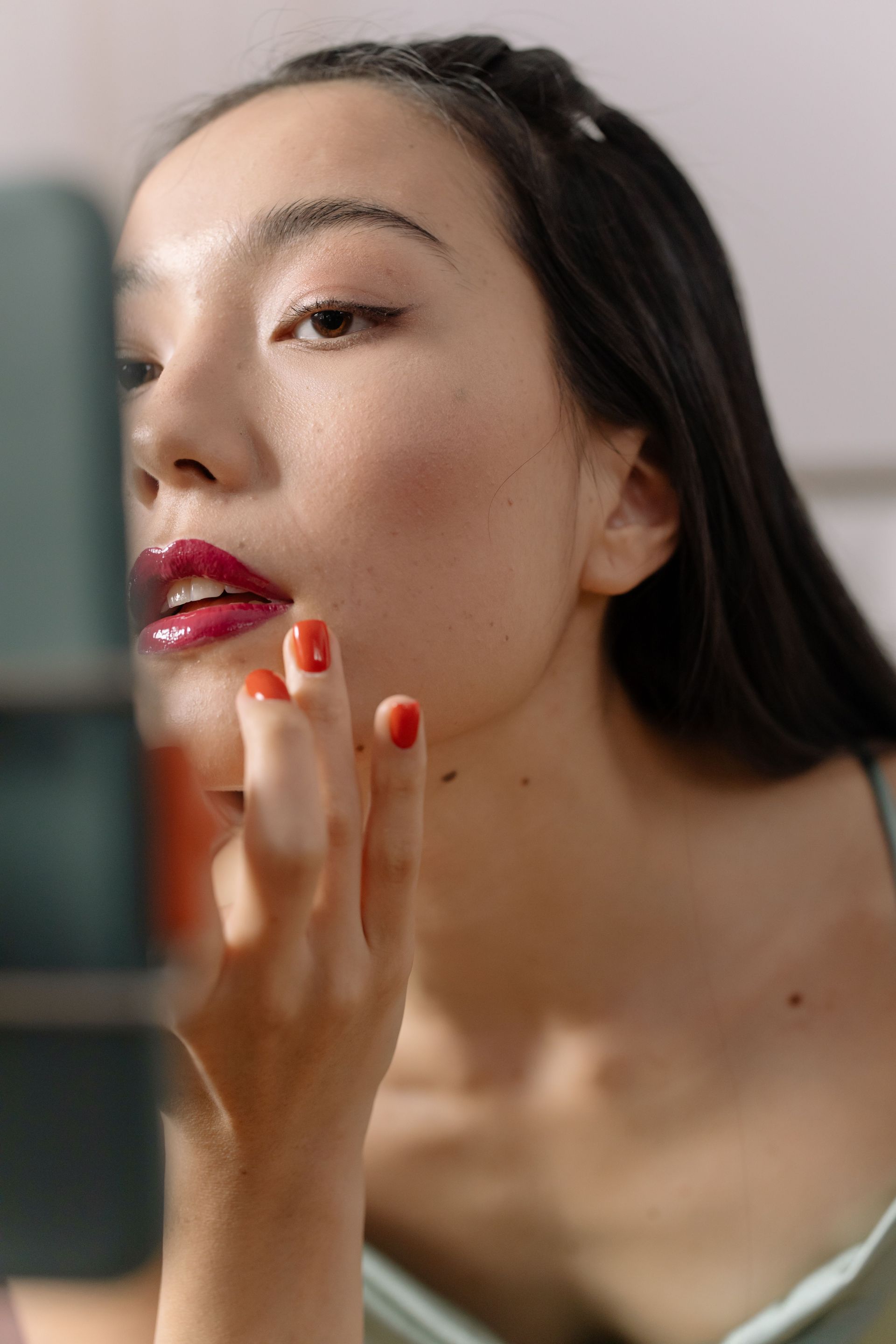 Mascara wand grooming an eyebrow above a brown eye