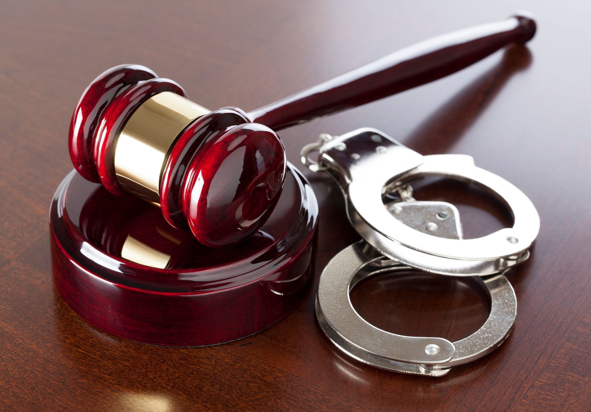 Wooden gavel and handcuffs on a wooden table, symbolizing legal proceedings and law enforcement.