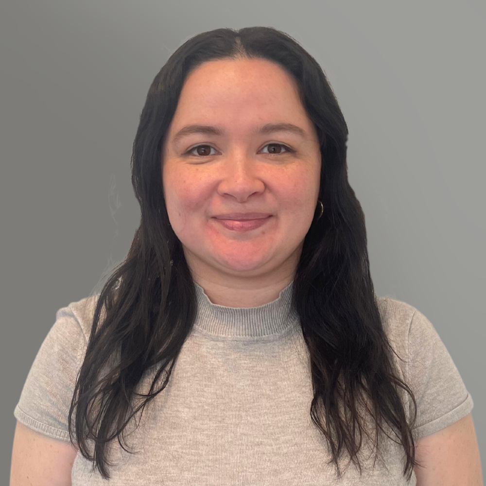 Smiling woman in a light gray shirt against a plain gray background