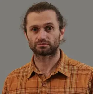Man in an orange plaid shirt against a plain gray background