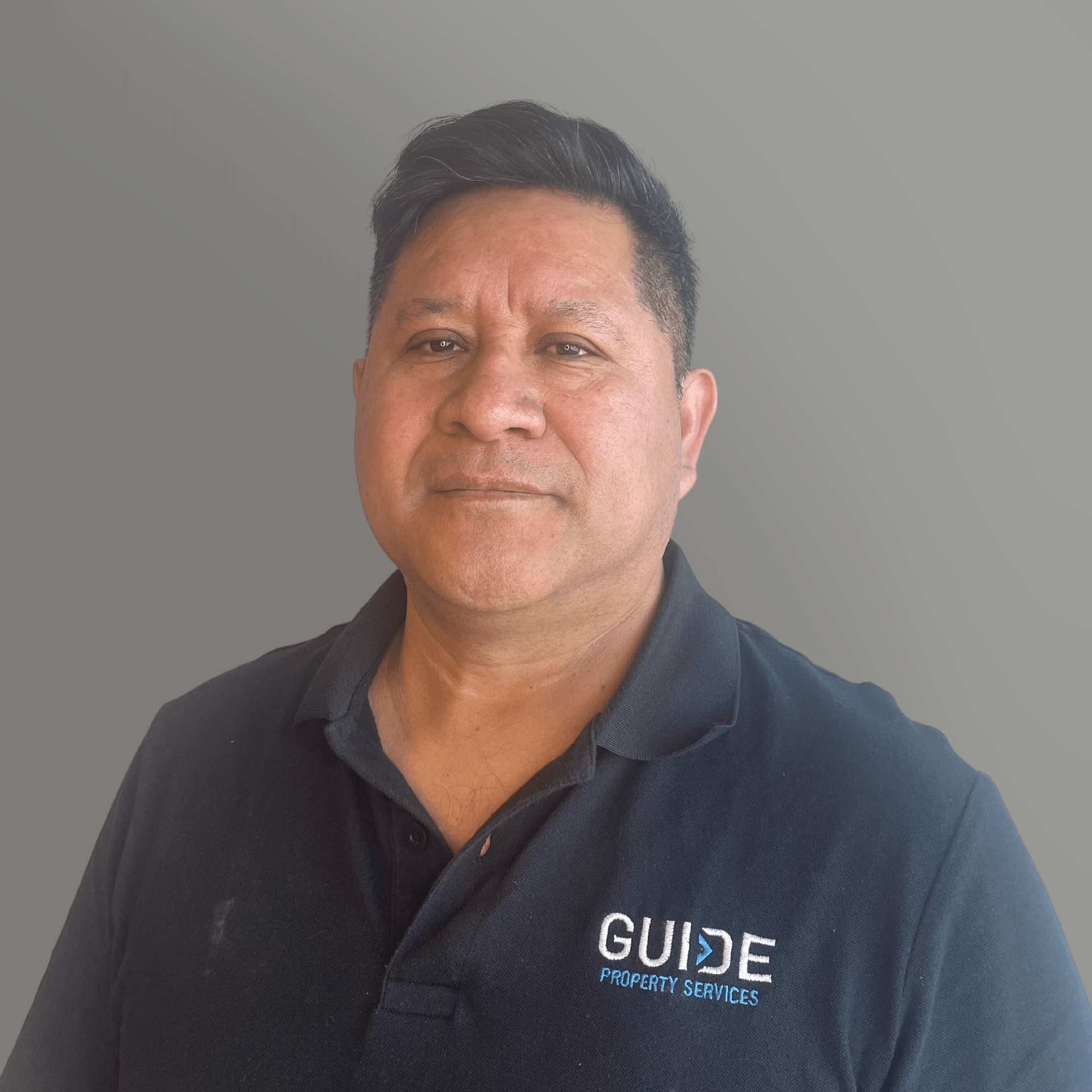 Man in a navy polo shirt against a plain gray background, facing forward with a neutral expression