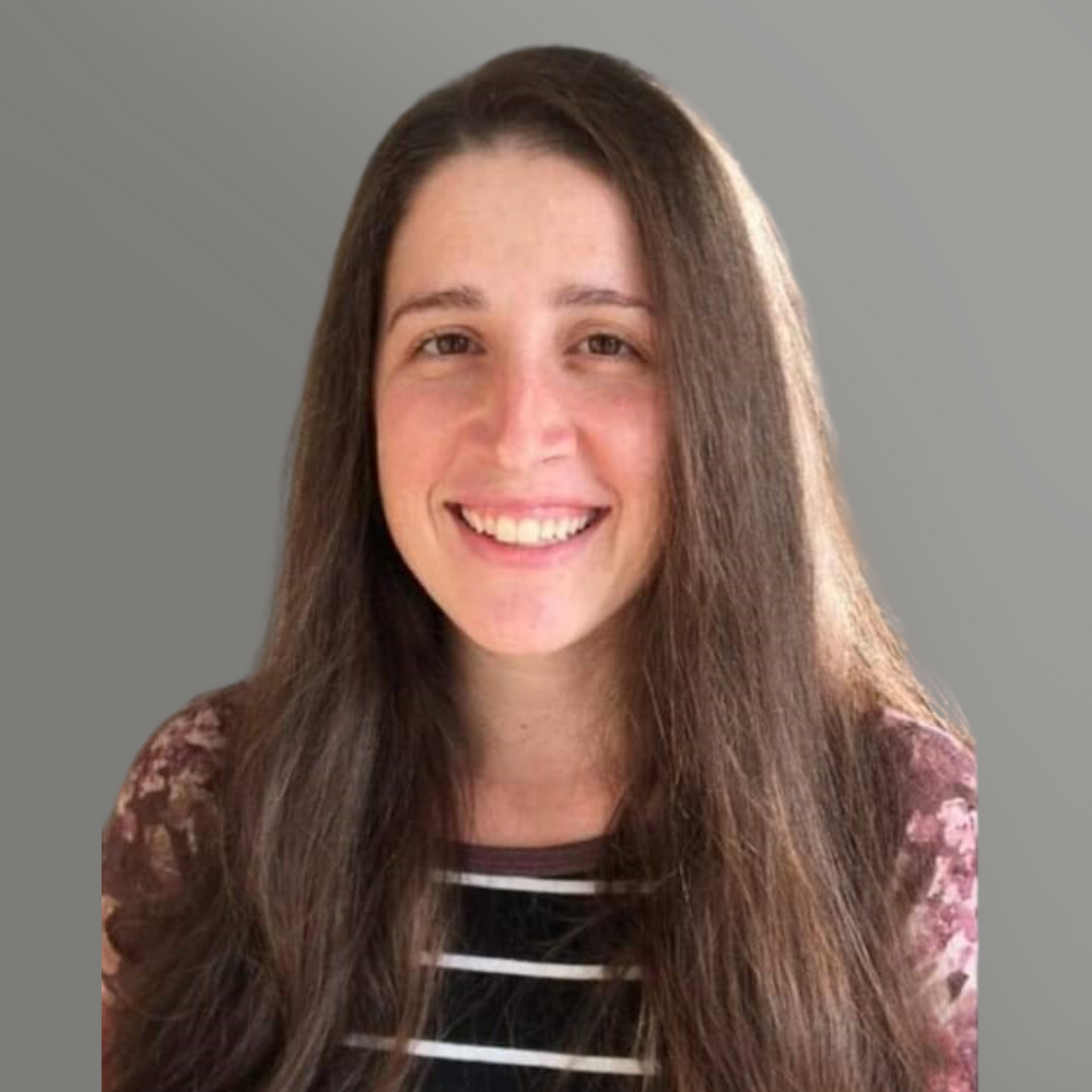 Smiling person with long brown hair in a striped shirt against a plain gray background