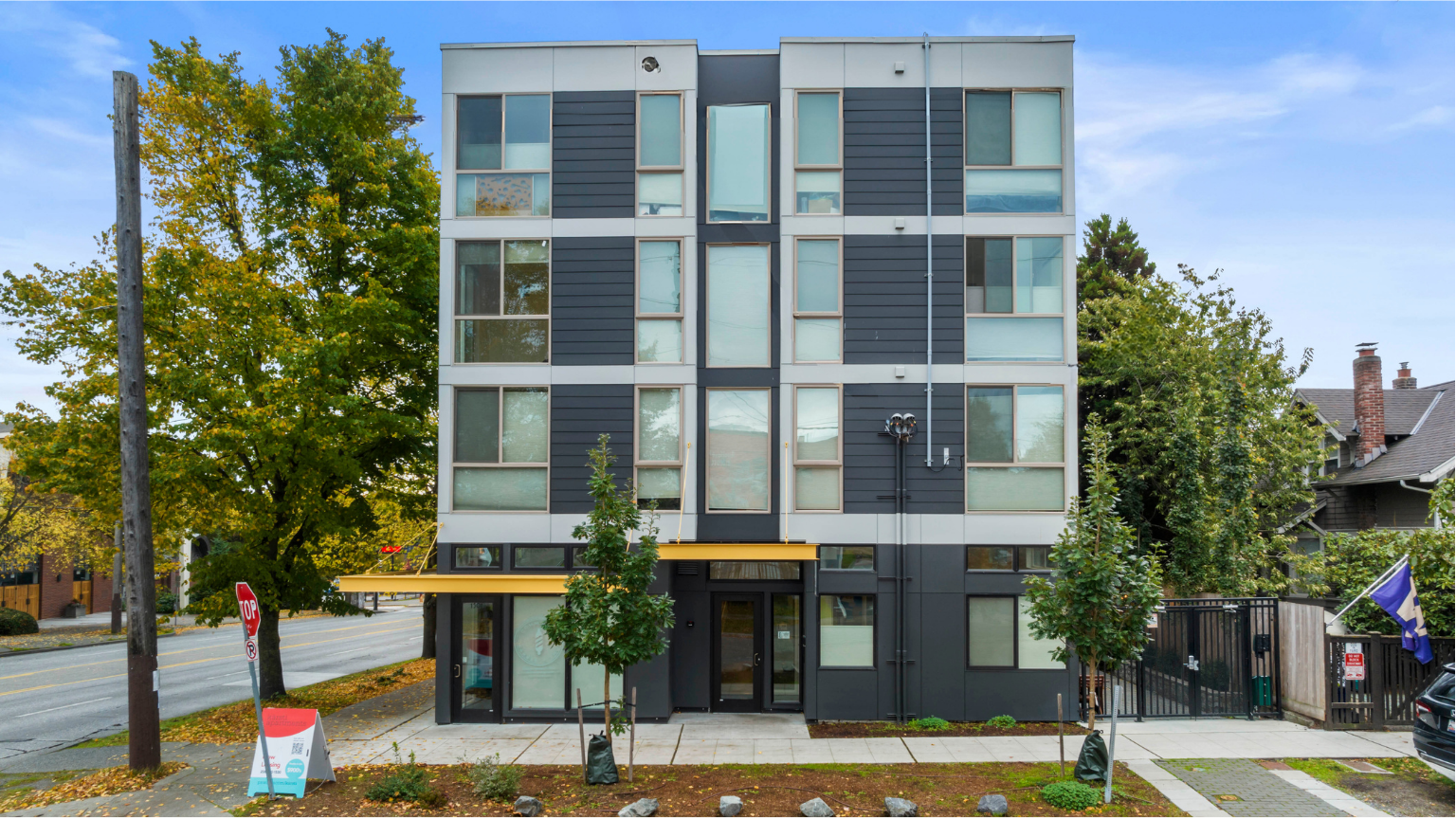 Modern gray apartment building with large windows on a tree-lined street