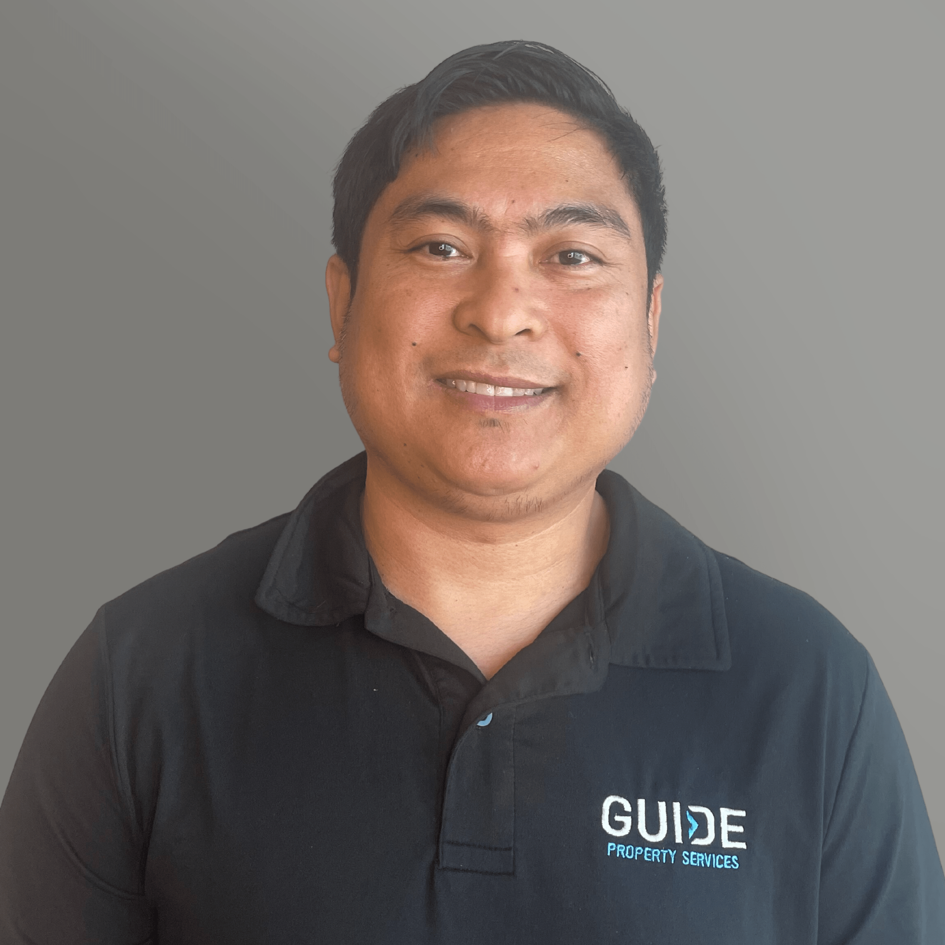 Smiling person in a black GUJIE polo shirt against a plain gray background