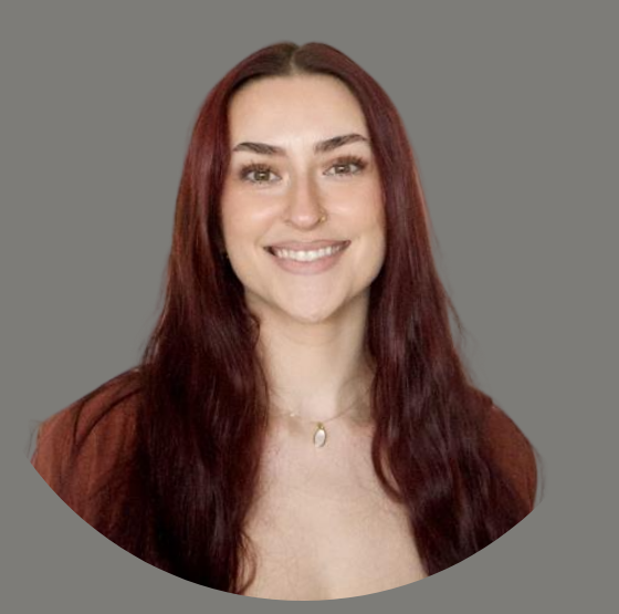 Smiling woman with long dark hair in a black top against a plain gray background