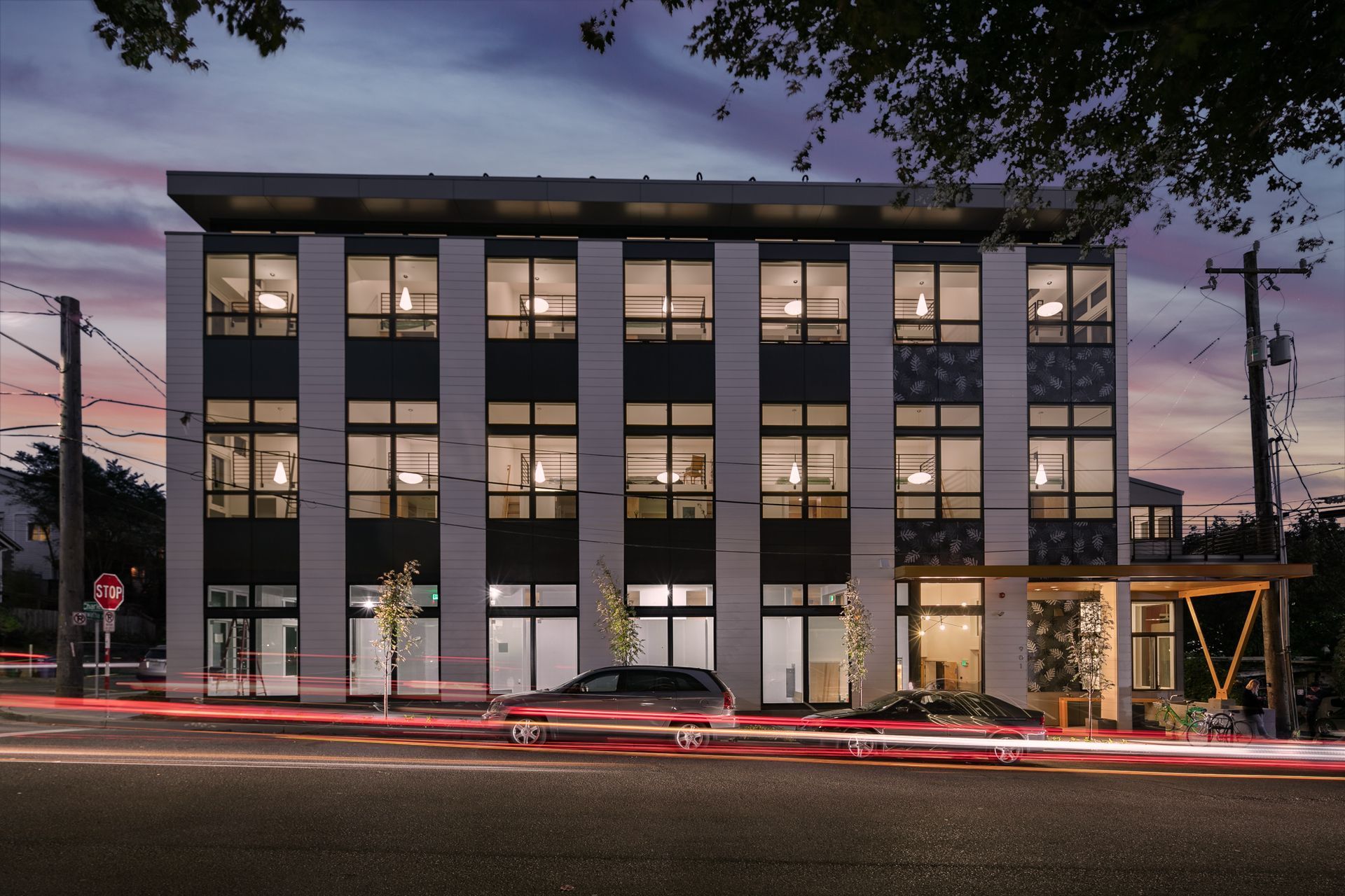 Modern office building at dusk with lit windows and passing car light trails