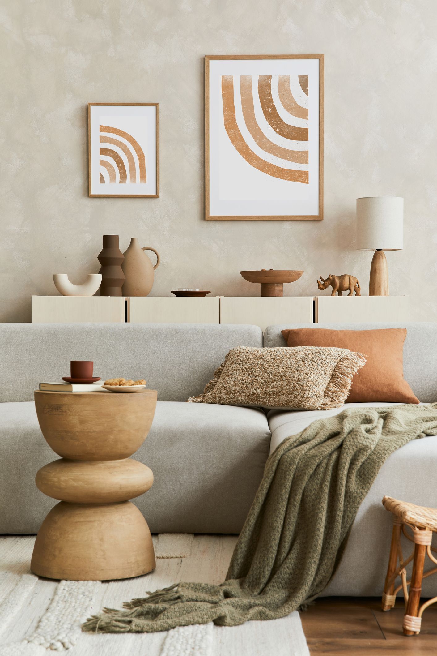 Neutral-toned living room with abstract art, beige sofa, wood table, and draped throw blanket