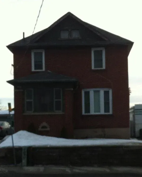 A brick house with a black roof and white windows