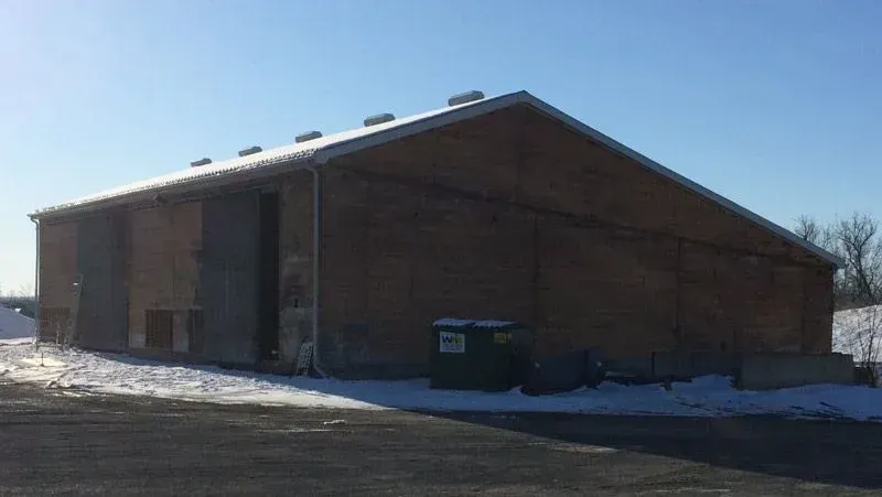 A large building with a trash can in front of it in the snow.