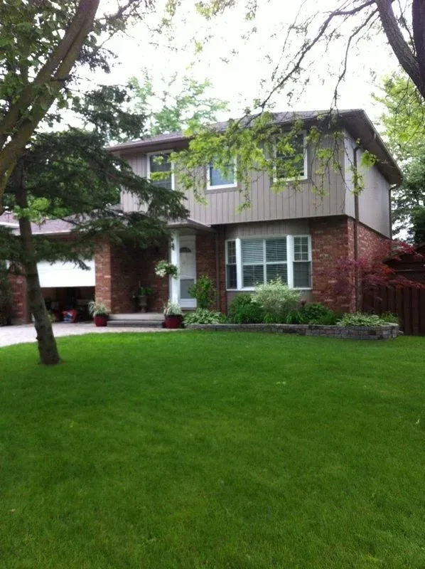 A brick house with a lush green lawn in front of it