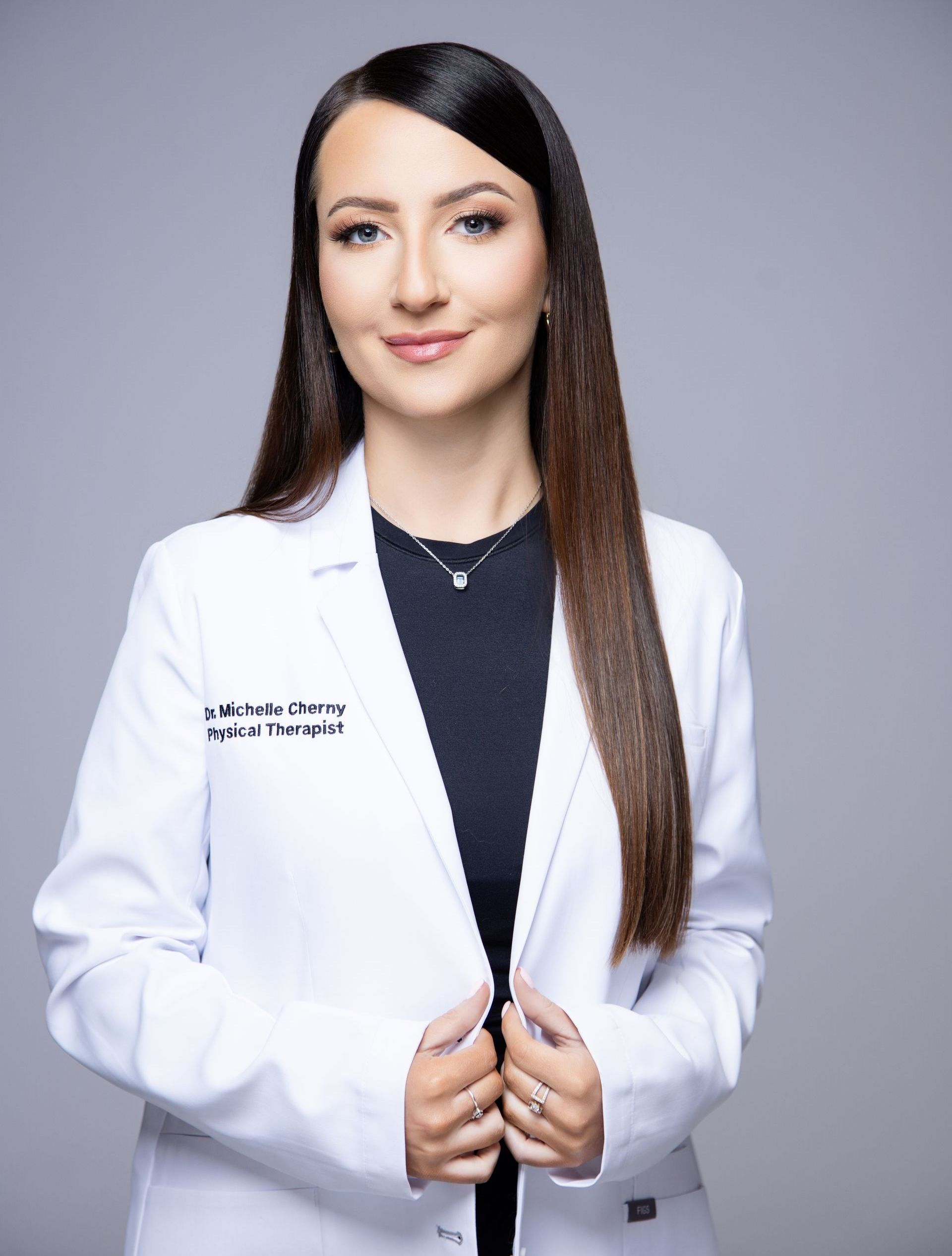 A woman is wearing a white lab coat and a black shirt.