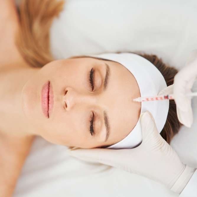 Person receiving a facial injection on the forehead, viewed from above.