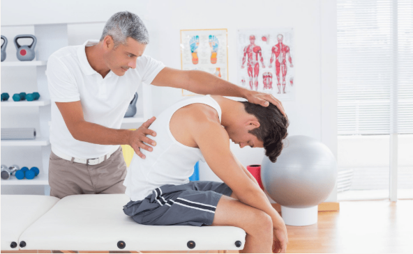 A man is sitting on a table getting a massage from a doctor.