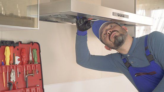 An experienced technician repairing a kitchen hood.