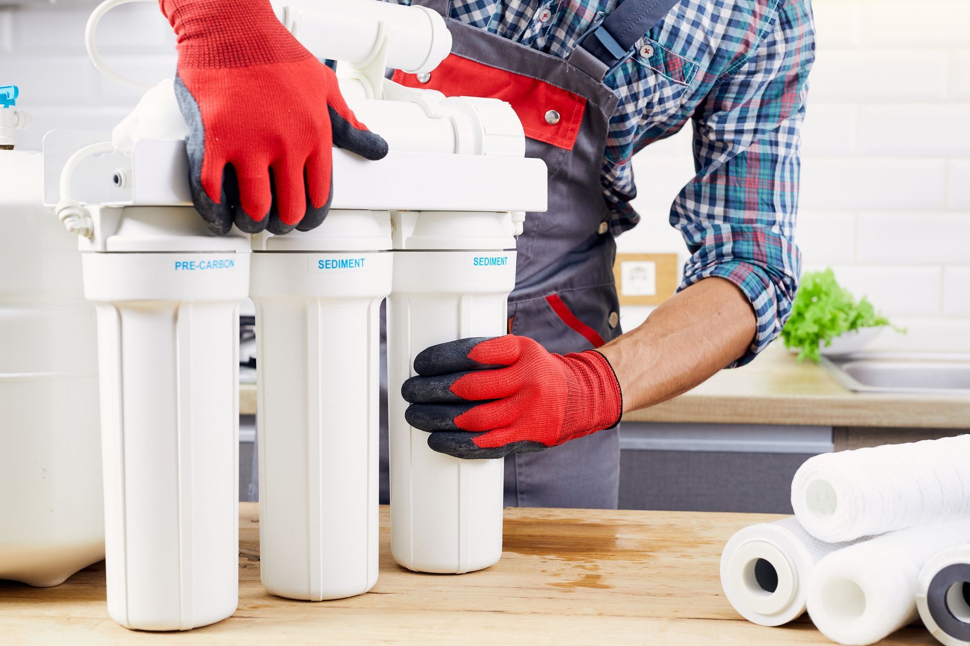 Water filter systems installation in progress by a water treatment specialist wearing red gloves. Water filter systems installation in progress by a water treatment specialist wearing red gloves.