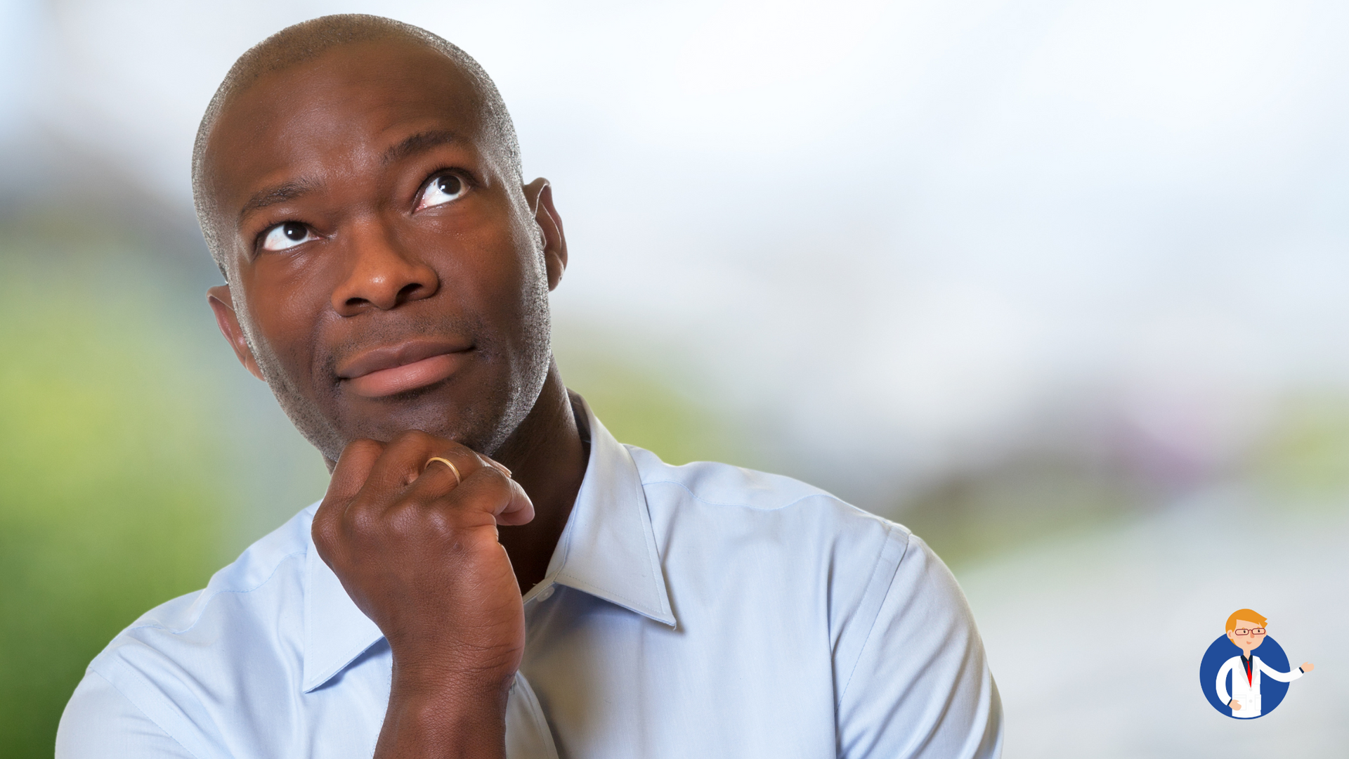 A man in a blue shirt is thinking with his hand on his chin.