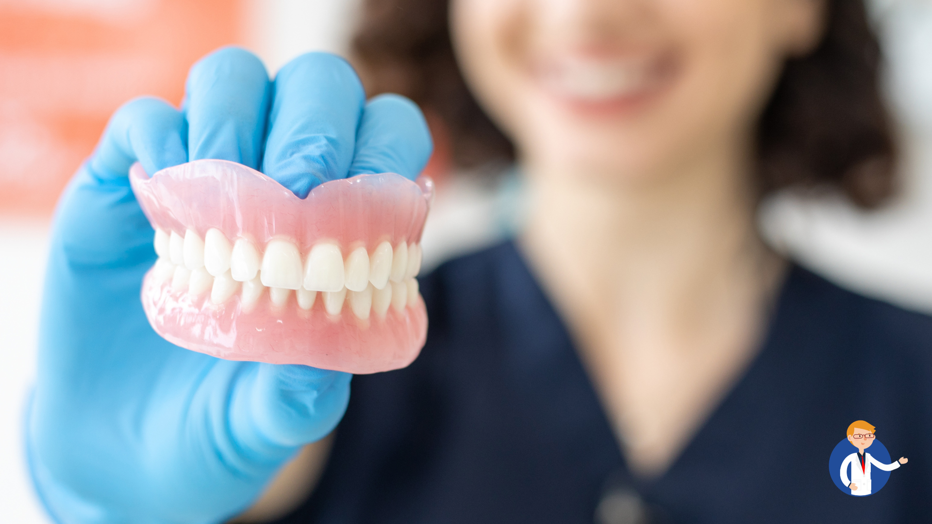 Person in blue gloves holding a set of dentures, smiling.