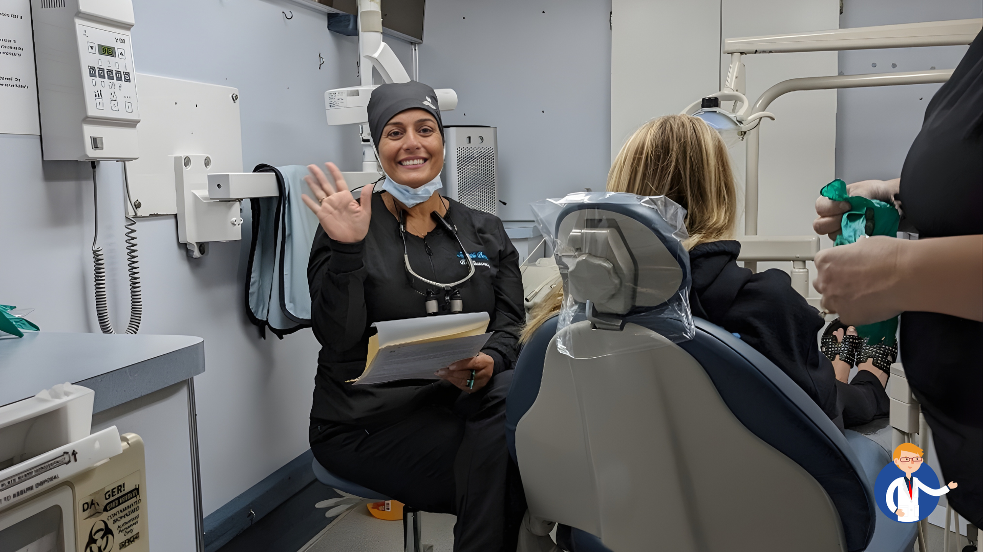 Dentist in black scrubs waves from dental chair, holding papers. Patient sits. Dental office setting.