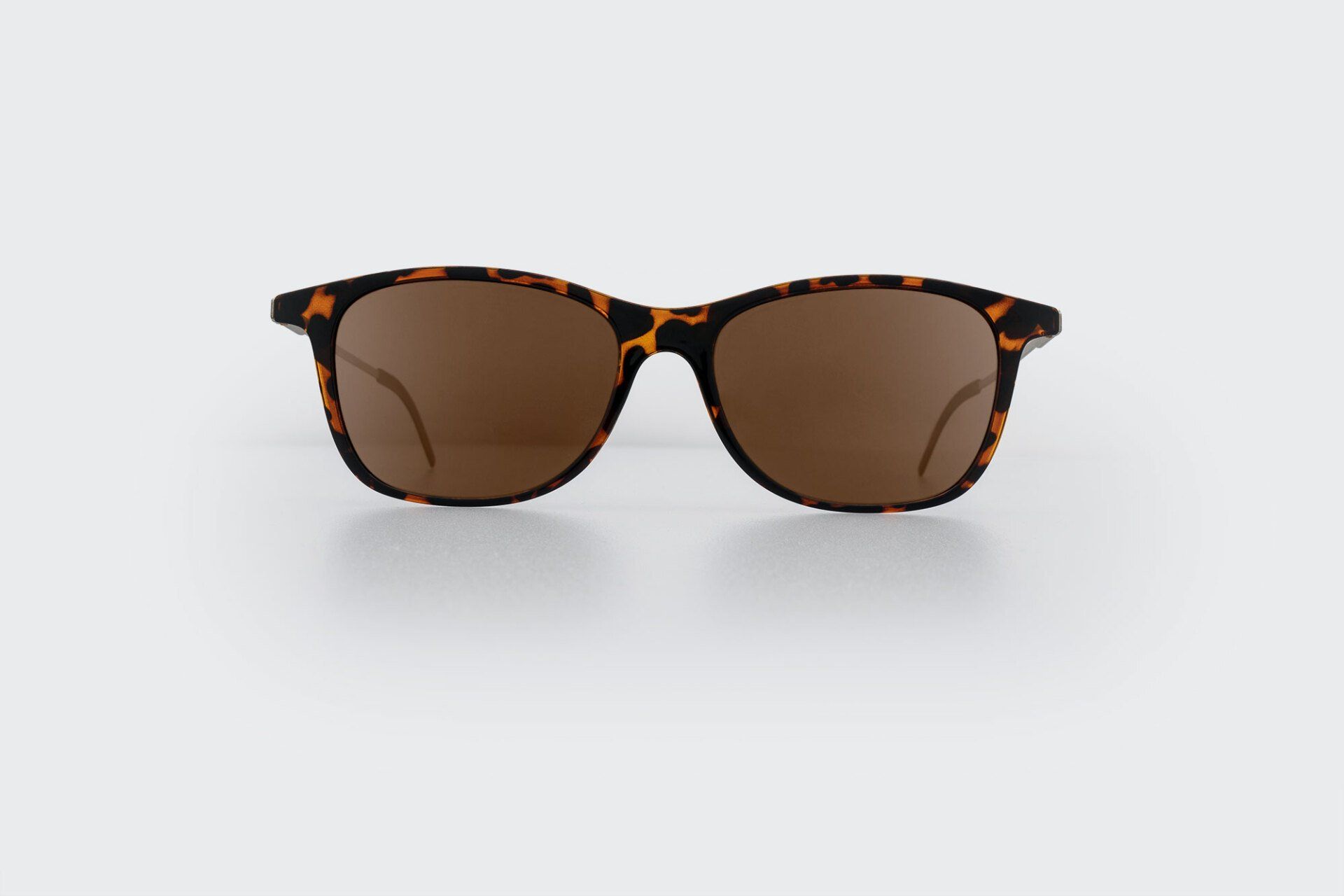 Sunglasses with brown lenses and tortoiseshell frame, resting on a white surface.