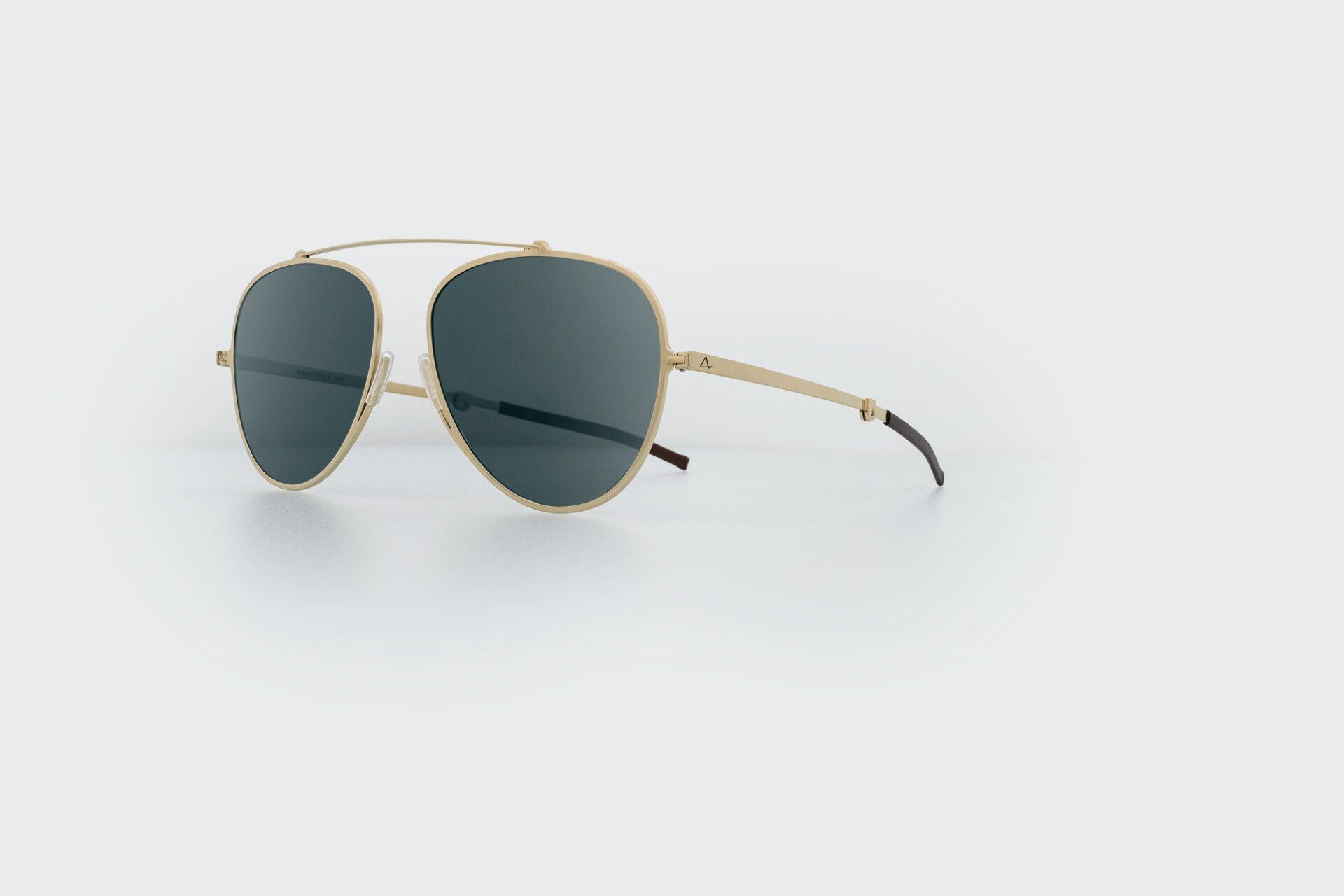 Gold aviator-style sunglasses with dark lenses on a white surface.
