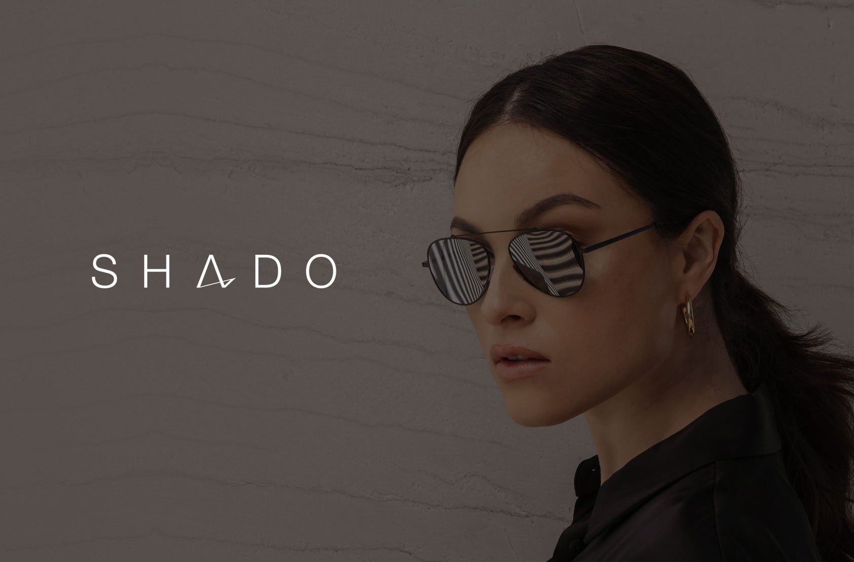 Woman wearing sunglasses, dark hair pulled back, logo