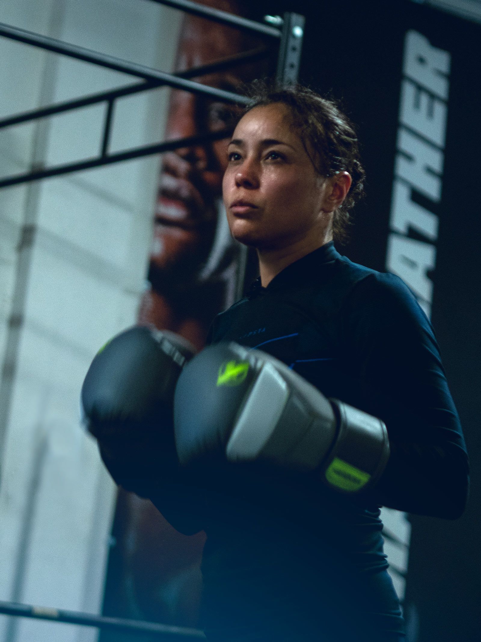 Boxer in a dark gym, wearing gloves, focused, ready to spar.
