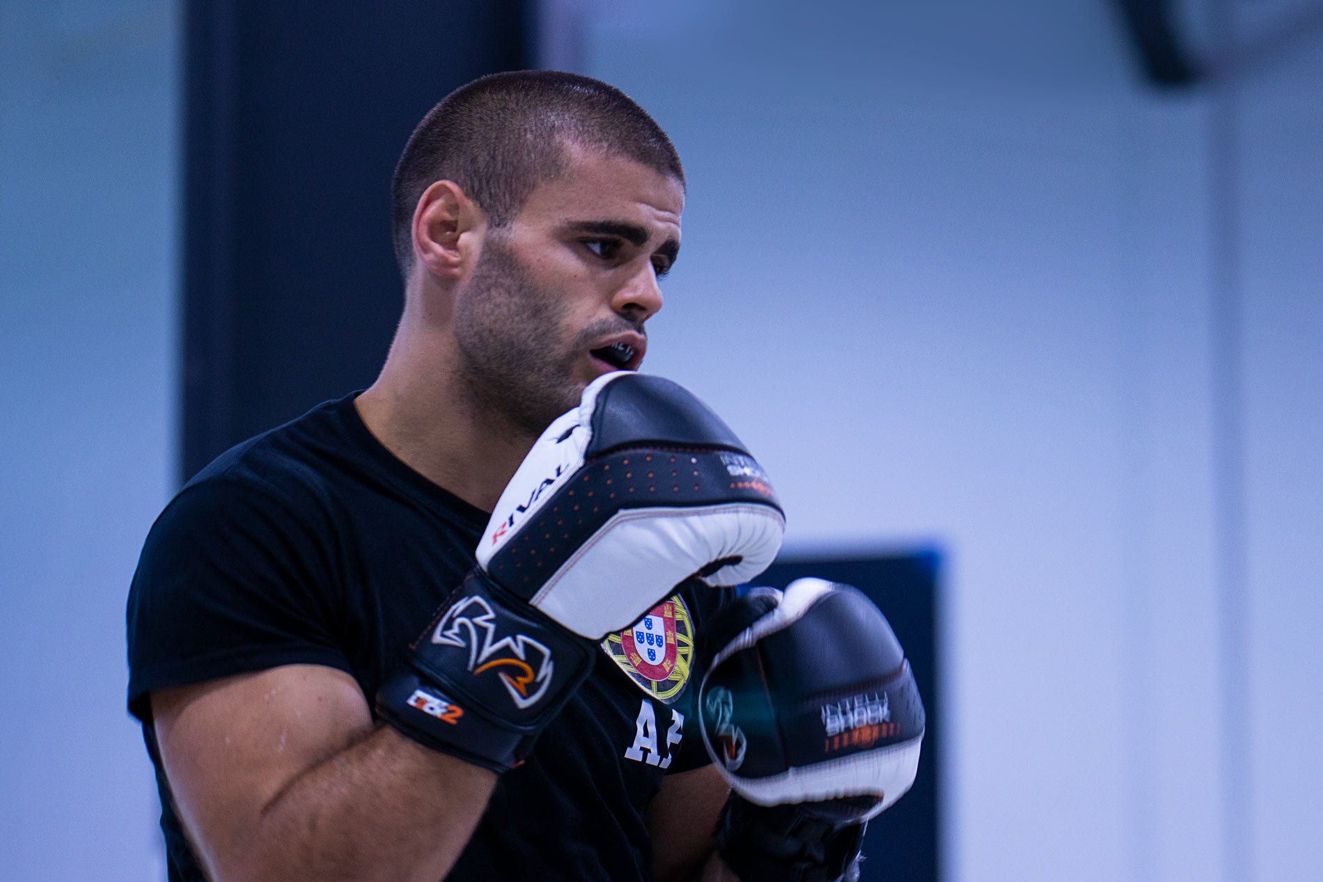 Boxer with gloves in training, looking focused with mouthguard in.