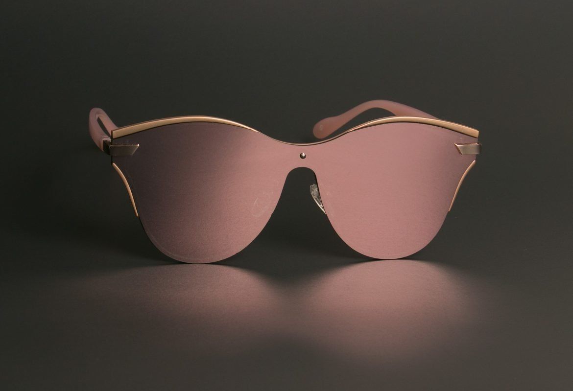 Pink mirrored sunglasses on a dark surface, with gold-toned accents.