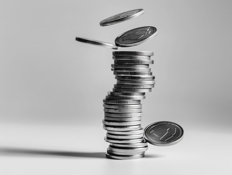 Stack of coins precariously balanced, with coins falling from above.