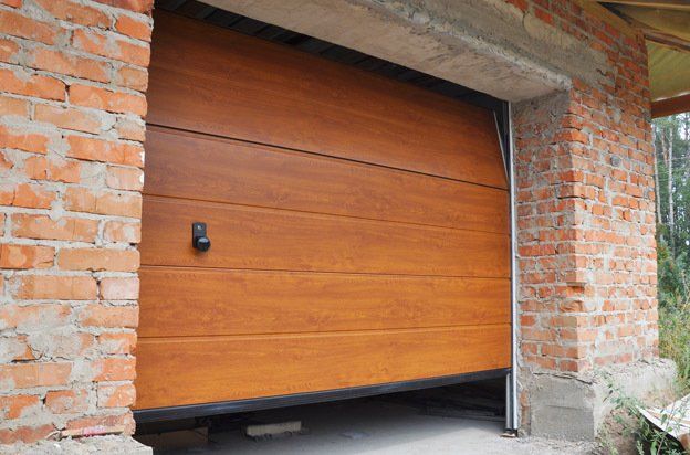 Sectional garage door with a wood-grain finish installed in a raw brick garage opening.